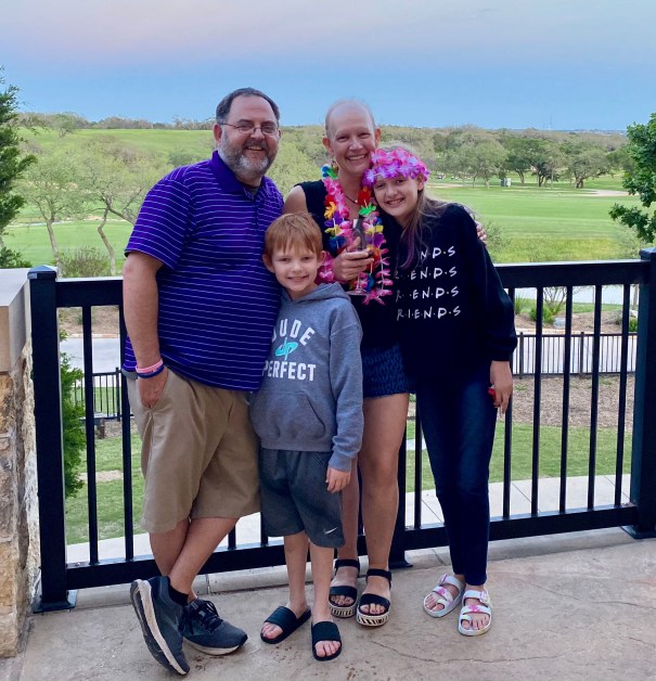 Family of four smiling with golf course in background