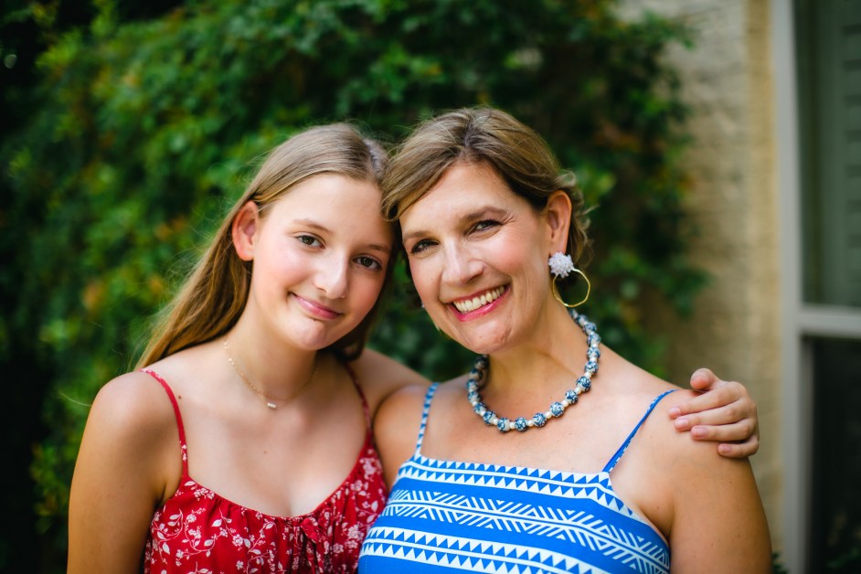 Teen daughter and mom hugging and smiling looking at camera